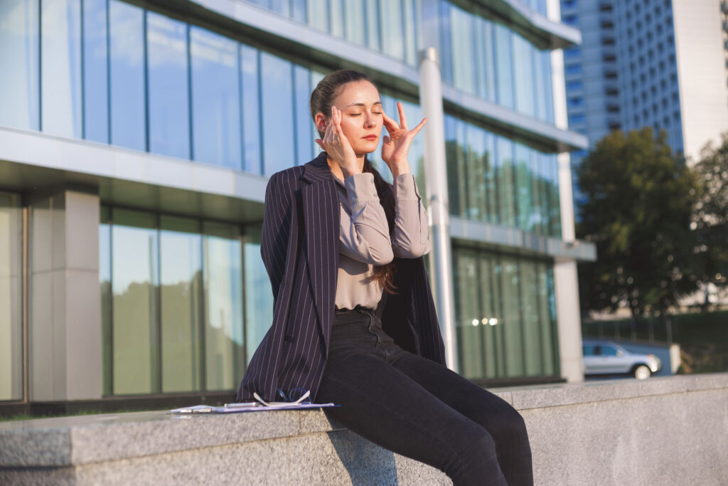 stressed out business woman sitting in front of office building