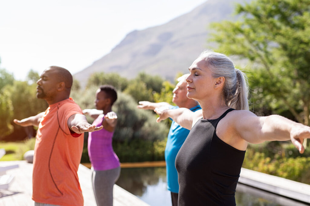 older men and women practicing Yoga breathing exercises outdoors