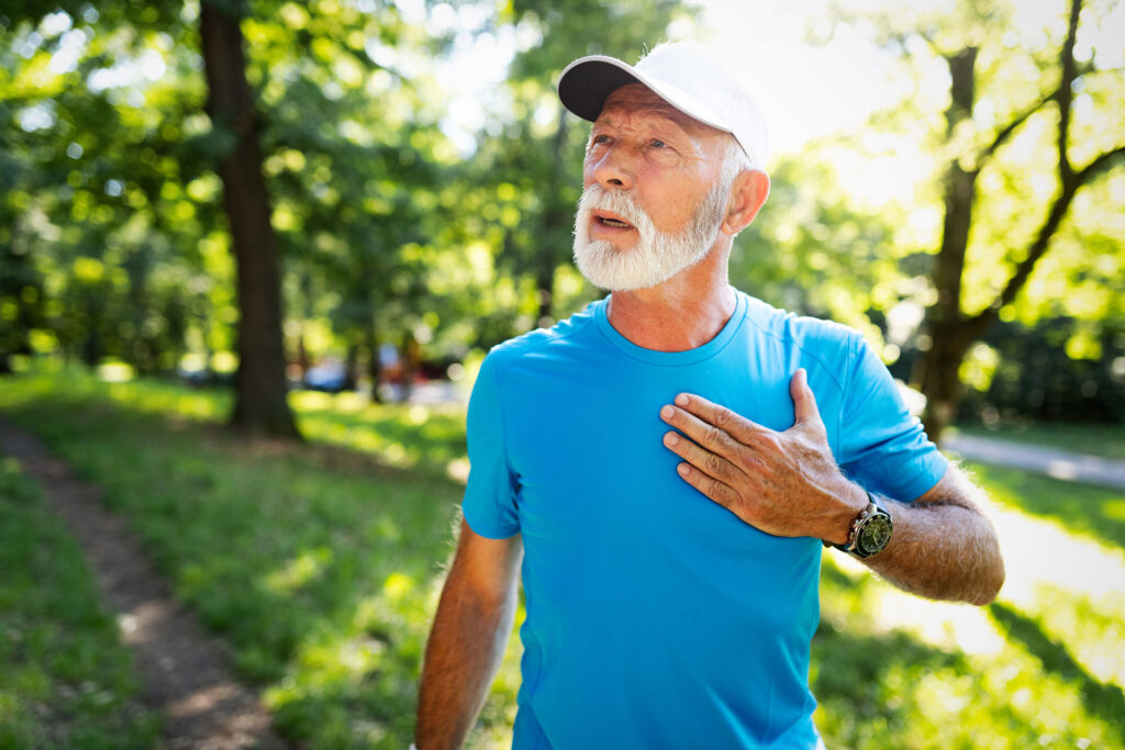 senior male holding heart after running outside