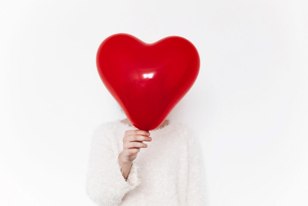woman holding heart shaped balloon in front of her face