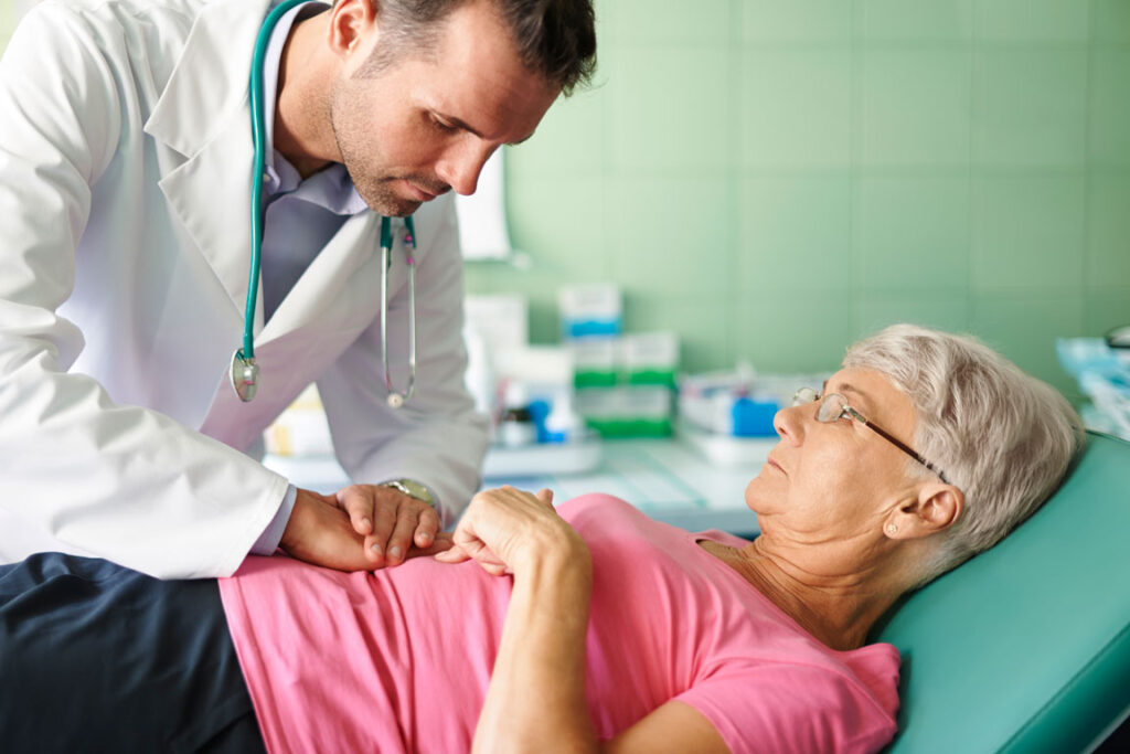 male doctor checking stomach health of senior female patient