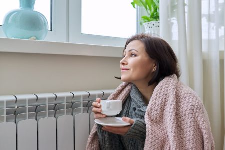 woman enjoying tea by the heater
