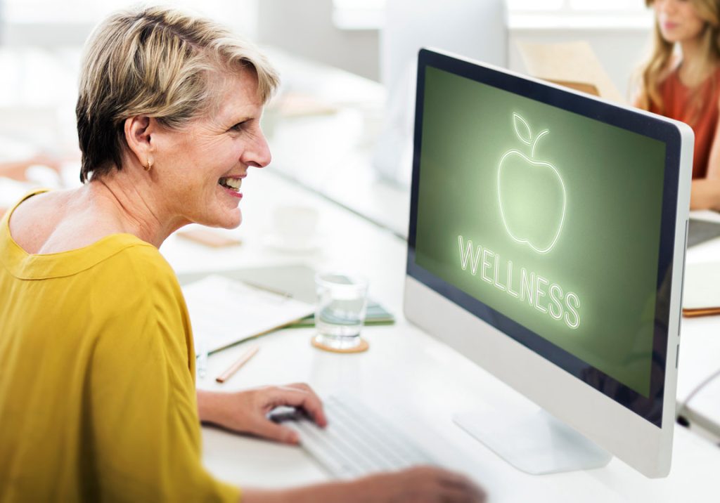 female professional looking at a desktop computer screen that says wellness