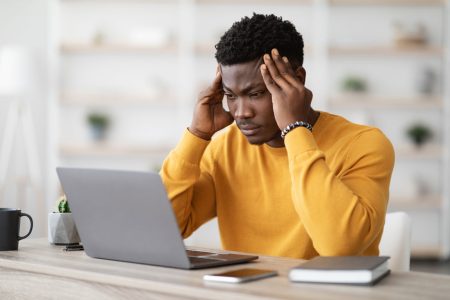 stressed African American male in front of laptop
