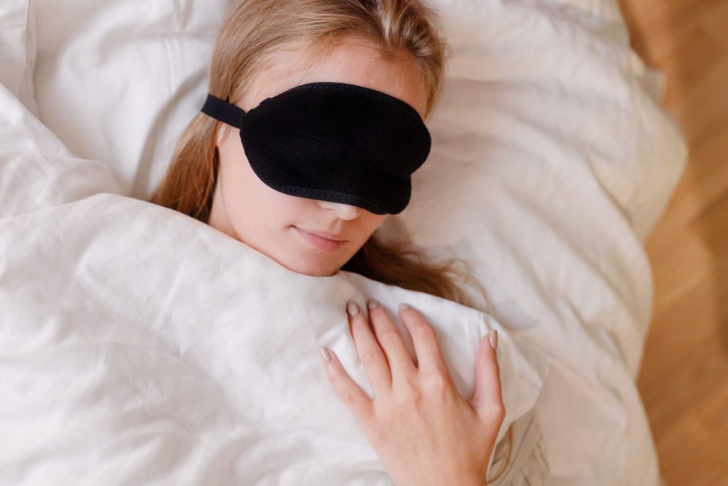 blond woman sleeping in bed with night shades