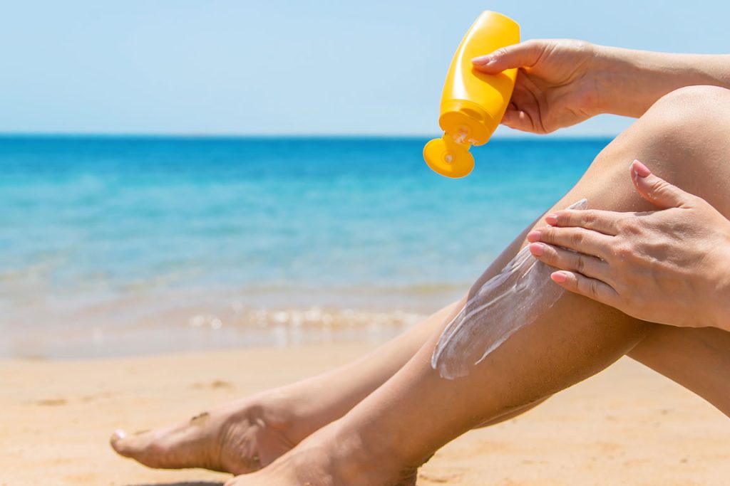 suntan-lotion applying suntan lotion to leg at the beach
